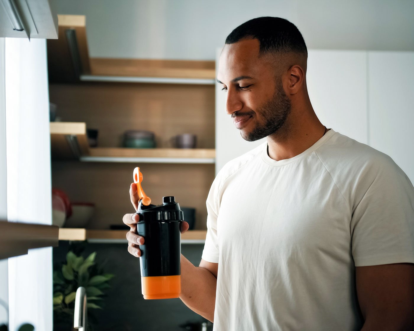 man-drinking-protein-in-kitchen