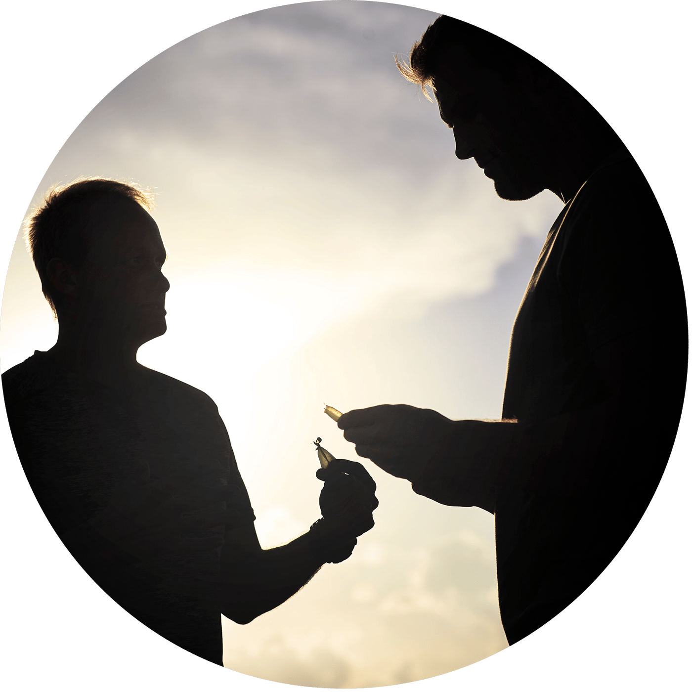 The image depicts a silhouette of one person handing another a bottle against a backdrop of a cloudy sky at sunset.
